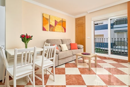 A living room with a sofa, chairs, a coffee table, and a vase of flowers.. Apartment 'Pilar Torre Del Mar' with Wi-Fi and Air Conditioning