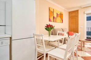 A modern kitchen with white appliances, a dining area with white chairs, a table, and a vase with flowers. - Apartment 'Pilar Torre Del Mar' with Wi-Fi and Air Conditioning (Torre del Mar)