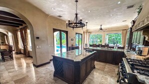 Una cocina amplia con una isla grande, muebles oscuros y una estufa a gas.