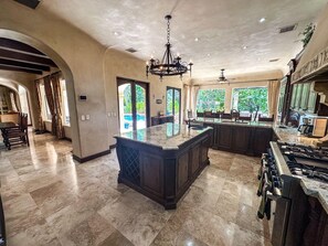 A spacious kitchen with a large island, dark cabinetry, and a gas stove. - Fantastic 6-bedroom Italian-Inspired Luxury Estate on the Reserva de Golf (CP)