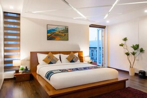 A modern hotel room with a large bed, a painting on the wall, a window with blinds, and a potted plant. - Sapa Paradise Hotel (Sa Pa)