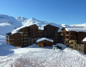 Ein mehrstöckiges Hotel mit Balkonen, umgeben von schneebedeckten Bergen.