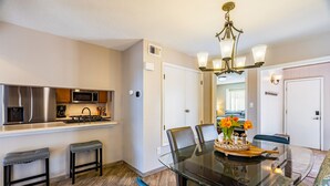 A dining area with a glass table, blue chairs, and a chandelier. - Taylor Ranch Respite - Modern, Light, Open Concept (Albuquerque)