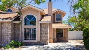 A two-story house with a brick facade, large arched windows, and a chimney. - Taylor Ranch Respite - Modern, Light, Open Concept (Albuquerque)
