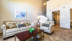 A living room with two sofas, a coffee table, a painting, and a staircase. - Taylor Ranch Respite - Modern, Light, Open Concept (Albuquerque)