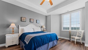 A bedroom with a bed, two bedside tables, a chair, a window, and a ceiling fan. - The Golden Hour Great Views (Branson)