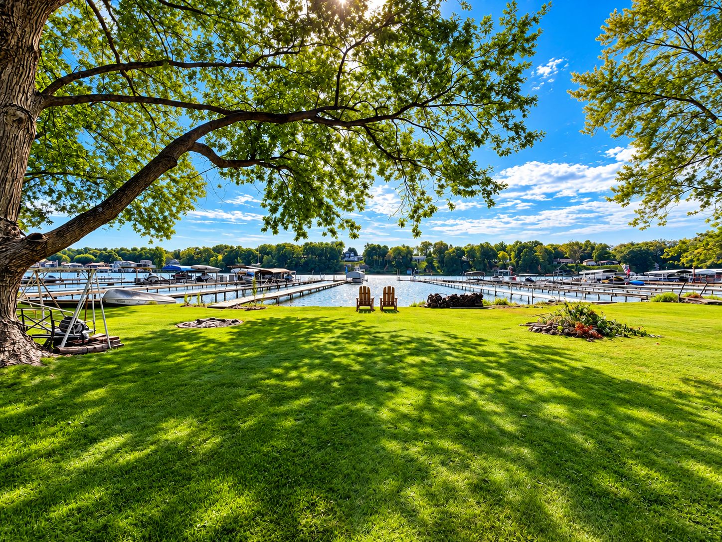 A lakeside view with a dock, boats, and a grassy area with chairs.