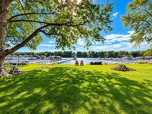 A lakeside view with a dock, boats, and a grassy area with chairs. - Cozy cottage with Lake Freeman access, within walking distance to Madam Carroll (Monticello)