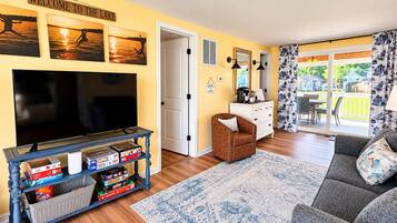 A living room with a TV, a coffee table, a sofa, and a rug.