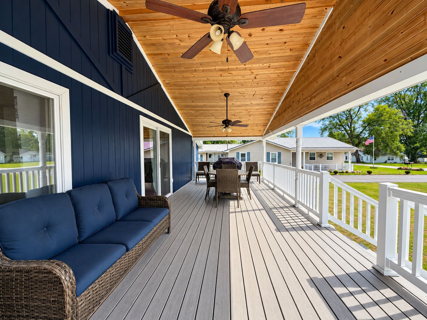 A covered porch with a ceiling fan, a dining table with chairs, and a blue sofa.