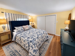 A bedroom with a bed, bedside tables, a nightstand, a lamp, a dresser, and a door. - Cozy cottage with Lake Freeman access, within walking distance to Madam Carroll (Monticello)