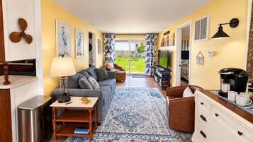 A compact living space with a sofa, coffee table, and a view of the outdoors.