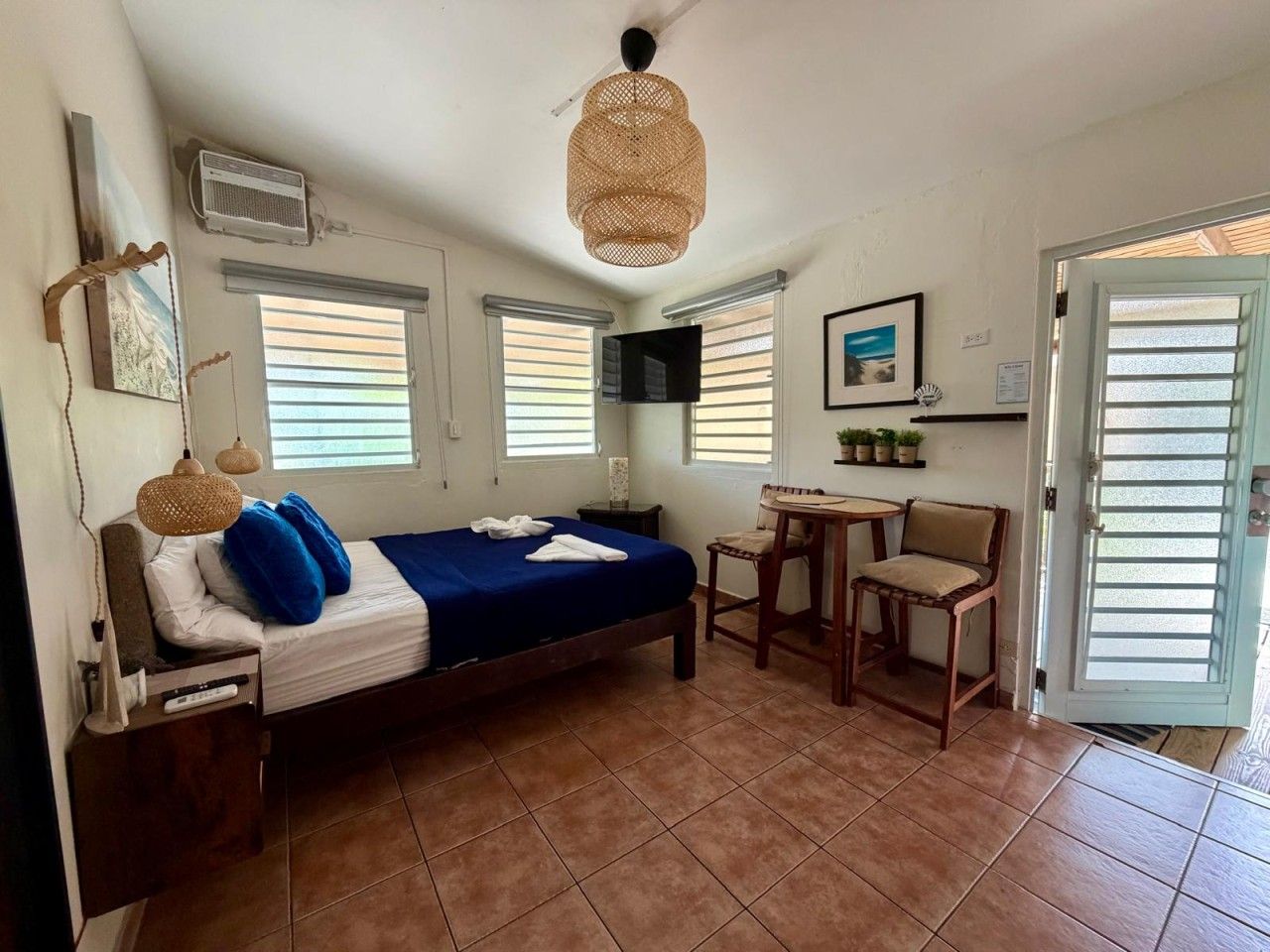 A bedroom with a bed, a desk, a chair, and a door.