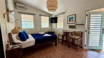 A bedroom with a bed, a desk, a chair, and a door.