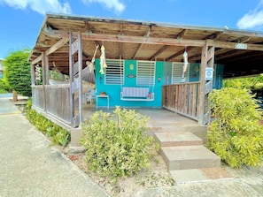 Un espace extérieur abrité, doté d’une structure en bois, d’un mur bleu et d’un petit coin salon.
