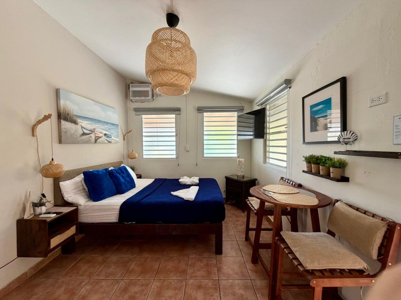A bedroom with a bed, bedside table, chair, and a small round table.