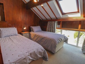 A room with two beds, a nightstand, a skylight, and a view of the outside. - Pearls Farm One (Macclesfield)