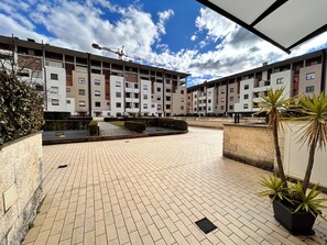 Ein Innenhof mit Fliesenboden, einem Baukran und mehrstöckigen Wohngebäuden im Hintergrund.