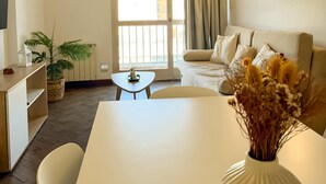 A modern living room with a sofa, a dining table, a TV, and a window with curtains. - Dpto en pleno centro de Salta con cochera (Salta)
