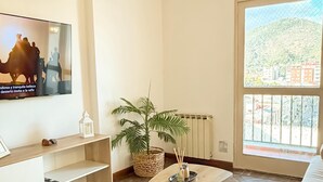 A living room with a TV, a plant, a wooden coffee table, and a sofa. - Dpto en pleno centro de Salta con cochera (Salta)