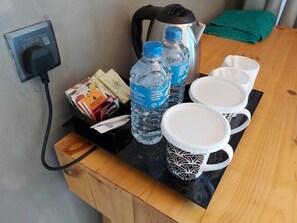 A countertop with a kettle, water bottles, a coffee maker, and a mug.