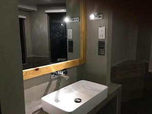 A bathroom with a white sink, a mirror with a wooden frame, and a wall-mounted light. - The Sun Coast Beach Resort - Mirissa (Mirissa)