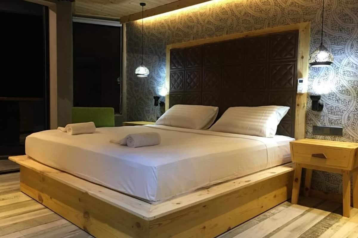 Una cama de madera con cabecera, dos mesitas de noche y un papel tapiz estampado.