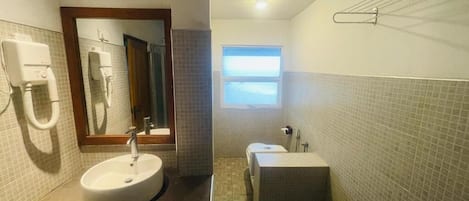 Un baño con lavamanos, espejo, toallero y ventana que proporciona luz natural.