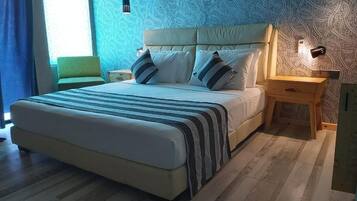 A bed with a striped blanket, a headboard, two bedside tables, and a patterned wall.
