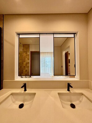 A bathroom with two sinks, a large mirror, and a view of a hallway. - Sunset Beach by Horizon Holidays (Black River)