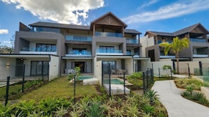 A multi-story hotel with balconies, a swimming pool, and a landscaped garden. - Sunset Beach by Horizon Holidays (Black River)