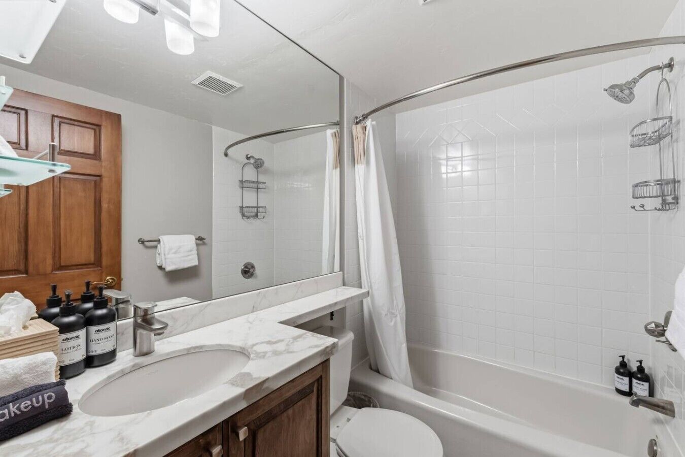 Un baño moderno con un espejo grande, dos lavamanos, ducha e inodoro.
