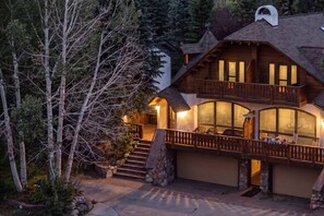 Eine zweistöckige Blockhütte mit Balkon, Steintreppe und Garage.