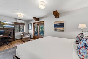 Ein Schlafzimmer mit einem großen Bett, einem Schreibtisch mit Computer, einem Sessel und einem Fernseher.