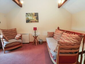 A cozy room with a bed, two chairs, a small table with a lamp, a picture on the wall, and a radiator. - Pearls Farm Two (Macclesfield)