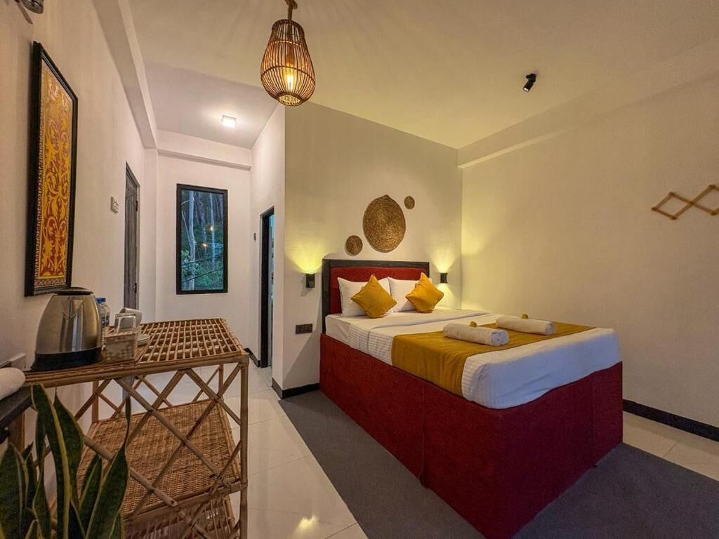 Habitación de hotel con cama, mesita de noche, lámpara y vistas al exterior.