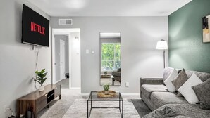 Uma sala de estar moderna com televisão de tela plana, sofá, mesa de centro e uma planta.