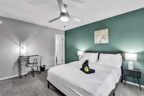 Una habitación de hotel con cama, escritorio, silla y dos lámparas de noche.