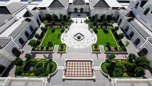 A symmetrical courtyard with a central fountain, surrounded by manicured gardens and a geometric tile pattern. - King Suite | Grand America | Grand Spa and Pool (Salt Lake City)