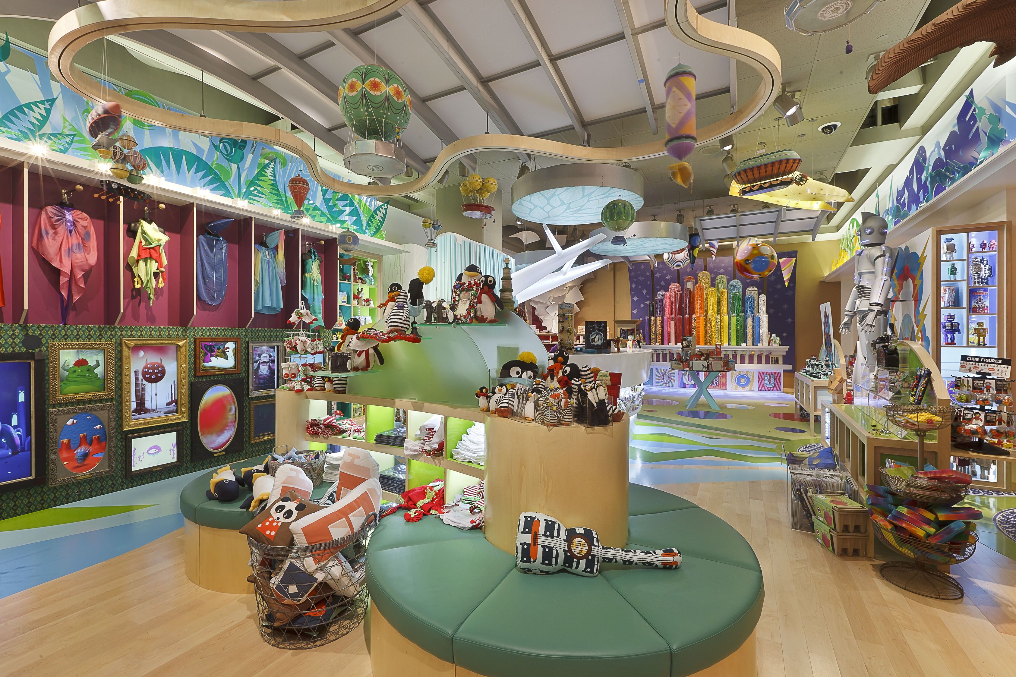 A colorful interior with a central seating area, shelves with various items, and a ceiling with unique lighting fixtures.