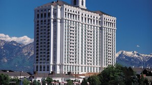 Ein Hochhaus-Hotel mit einem zentralen Turm, mehreren Balkonen und einer Bergkulisse im Hintergrund.