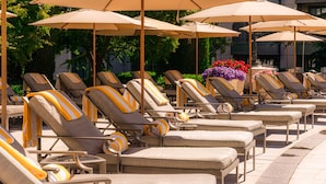A row of sun loungers with striped cushions, arranged in a line with large umbrellas overhead.
