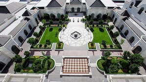 A symmetrical courtyard with a central fountain, surrounded by manicured gardens and a geometric tile pattern.