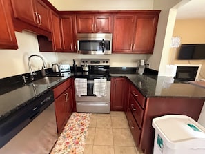 A kitchen with wooden cabinets, a stainless steel oven, a microwave, and a toaster.