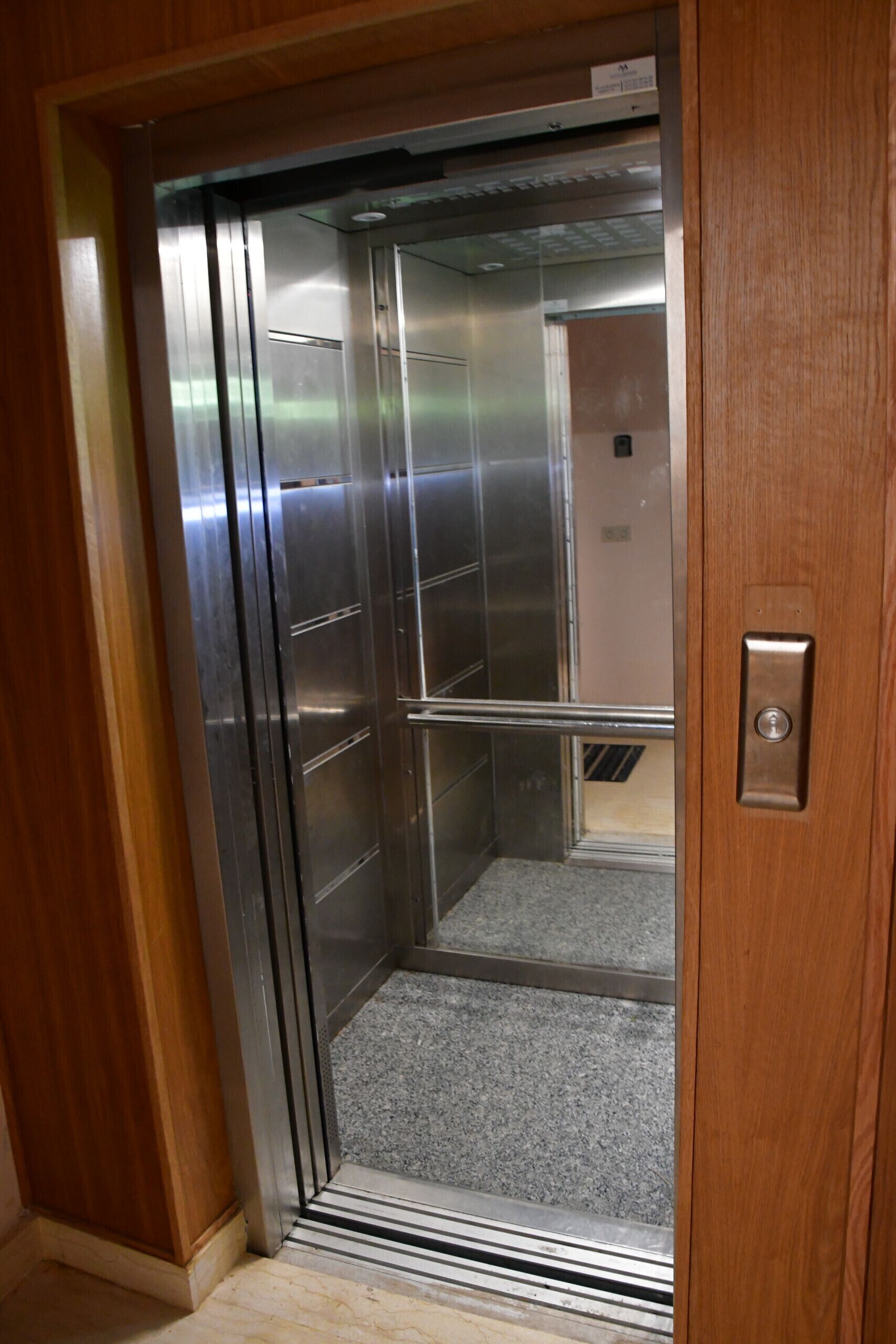 Een lift met metalen deuren en een metalen handgreep.