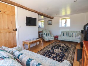 A living room with a sofa, armchairs, a coffee table, a TV, and a patterned rug. - The Granary (York)