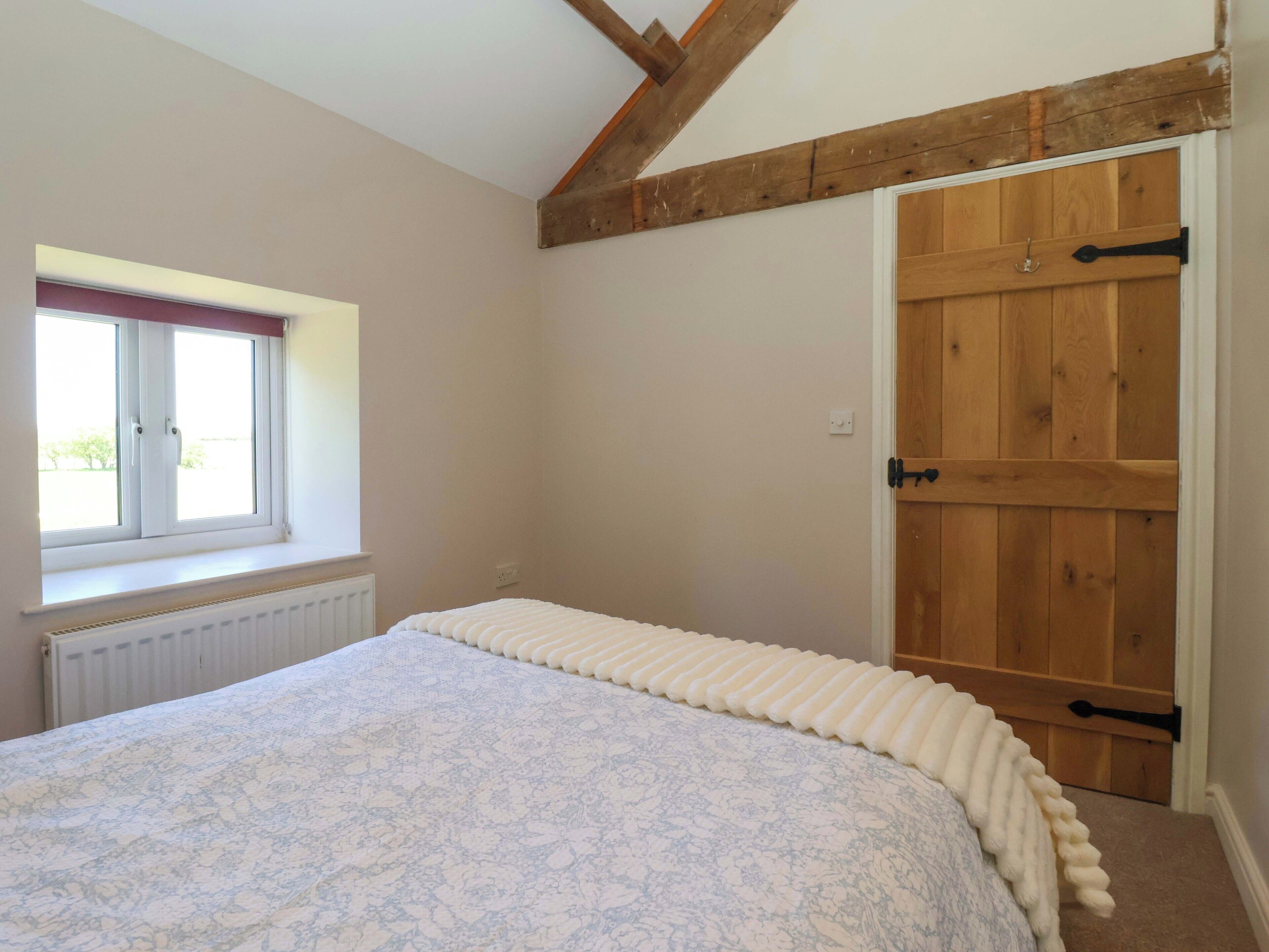 Een slaapkamer met een bed, een raam, een radiator en een houten deur.