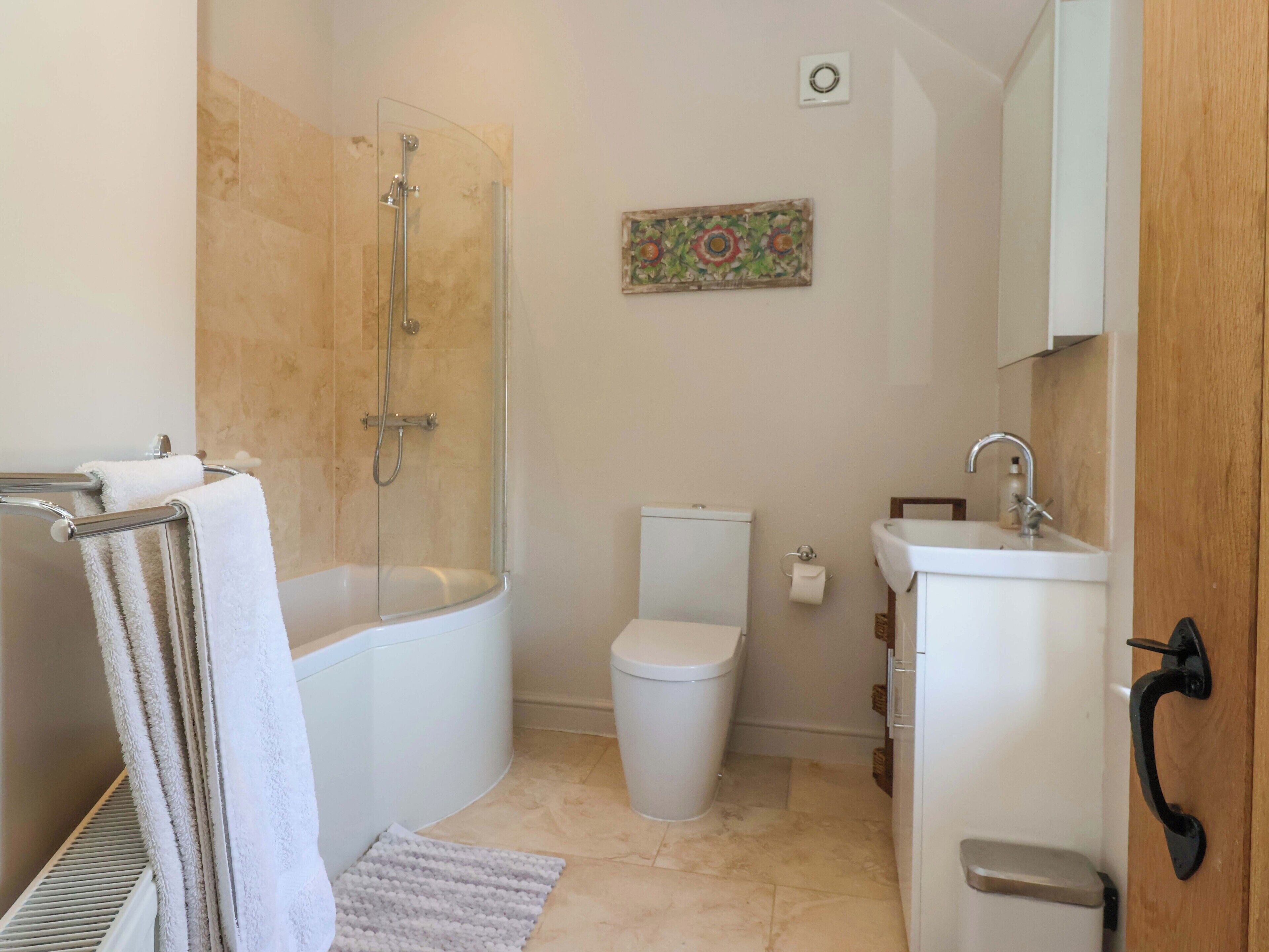 Baño con ducha, inodoro, lavabo y toallero.
