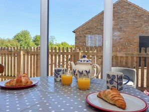 A table with a polka dot tablecloth, a teapot, two cups, and two croissants. - The Granary (York)