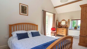 Un dormitorio con cama, cómoda, espejo y ventana con cortinas.